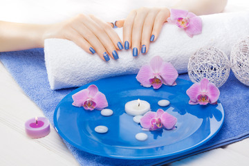 Obraz na płótnie Canvas beautiful blue manicure with orchid and towel on the white wooden table. spa
