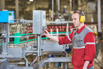 Factory worker operating conveyor with beer beverage bottles moving