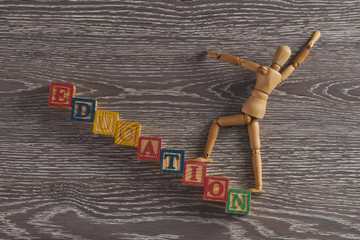Education concept. Wooden figurine on stairs made of wooden cubes with letters