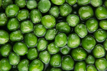 Wet fresh green peas in water closeup as background. Healthy vitamin food.