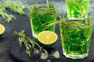 Green cocktail with lime, soda, crushed ice and tarragon leaves.