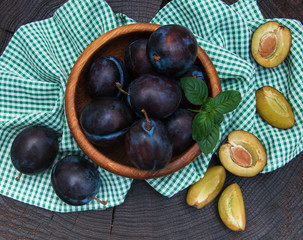 Bowl with  plums with green leaves