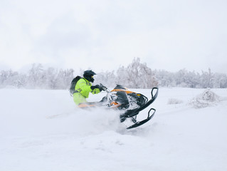 Athlete on a snowmobile moving in the forest