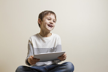 Cute playful happy child with digital tablet computer playing games.