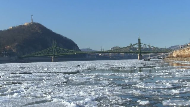 Ice debacle landscape of the river Danube in Budapest. The footage shows an old bridge and the hill Gellert with the statue of liberty.