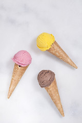 Various ice cream cones are on the marble surface.