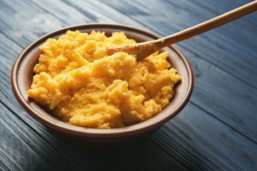 Corn porridge in plate on wooden background, closeup