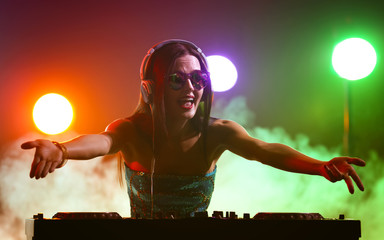 Pretty young DJ playing music in nightclub