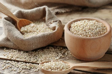 Deurstickers Brown short grain rice on wooden table closeup © Africa Studio