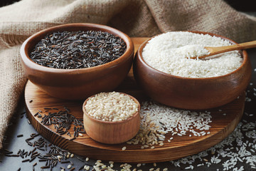 Different types of rice in bowls on grey table closeup