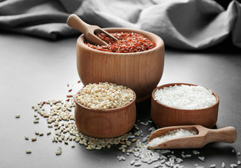 Different types of rice in wooden bowls on grey table