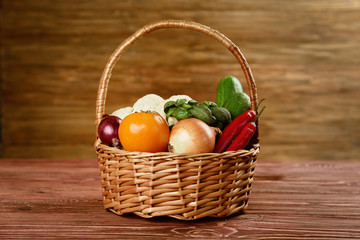 Fresh vegetables in wicker basket on wooden background