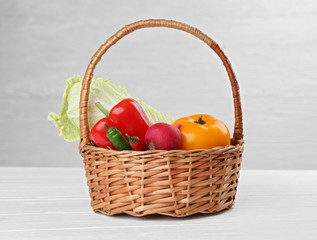 Fresh vegetables in wicker basket on wooden background