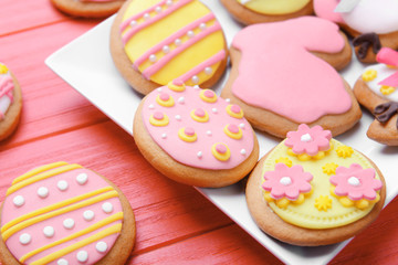 Plate with delicious Easter cookies on red wooden background, closeup
