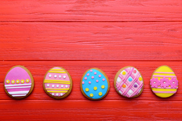 Colourful tasty Easter cookies in a row on red wooden background
