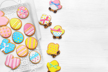 Fototapeta na wymiar Delicious colourful Easter cookies on tray and white wooden background