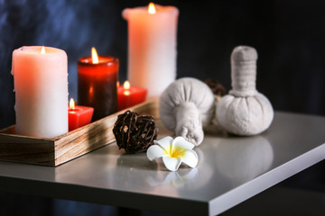 Fototapeta na wymiar Candles and herbal massage stamps on table in spa salon