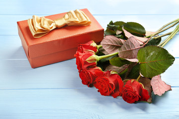 Beautiful red roses and gift box  on wooden background