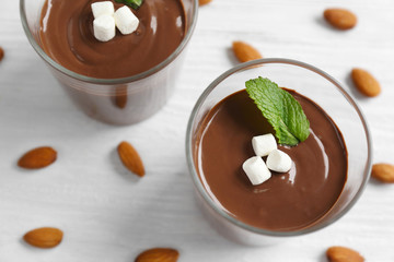 Chocolate mousse with marshmallows in portion glasses on wooden background