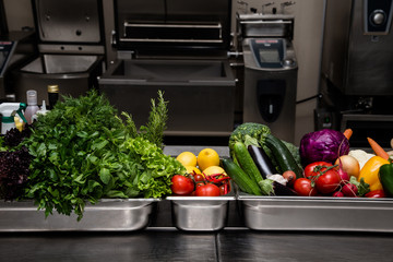 Fresh greens in metal bowl on professional kitchen. Selective fo