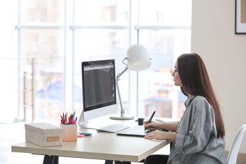 Naklejka premium Young female designer working in office