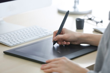 Female hands using graphic tablet in office