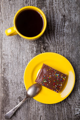 Tasty chocolate waffle cake and yellow cup of coffee on old wood