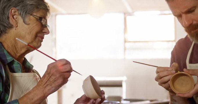 Male and female potter painting pots