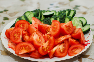 sliced tomatoes and cucumbers lie on a plate, close-up