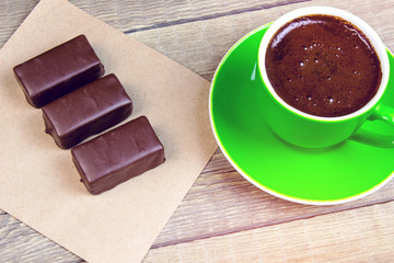 A few chocolates on a piece of paper with coffee Cup on wooden t