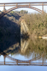 arch of iron bridge reflected in Adda river at Paderno, Italy