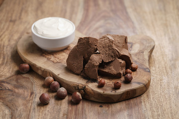 chunks of gianduja with hazelnuts and cream on wood board, premium chocolate dessert