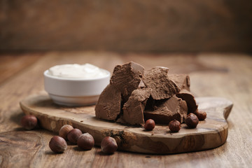 chunks of gianduja with hazelnuts and cream on wood board, premium chocolate dessert