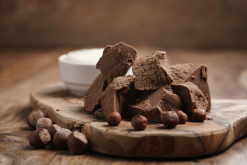 chunks of gianduja with hazelnuts and cream on wood board, premium chocolate dessert