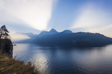 Alps of central Switzerland. Grand game of light and shadow. Sunlight sat behind a mountain ridge. Rays of light pierce the. Extra wide lens