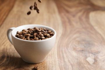 cappuccino cup with roasted coffee beans on wood table, with copy space