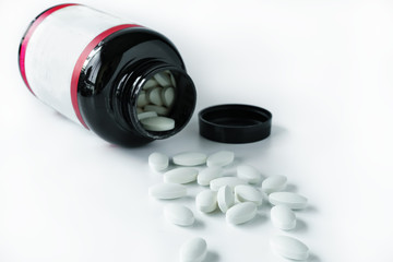 Pills and medicine bottle on white background
