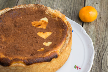 Baked cheesecake sprinkled with cocoa with heart shapes on cake