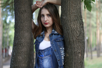 Woman in overalls stands between tree trunks