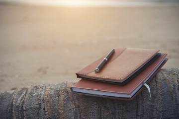 Notebooks,books and pen on the beach.