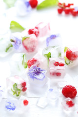 Ice cubes with raspberries and mint leaf on wooden table