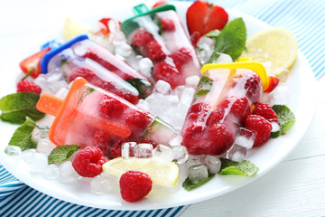 Popsicles with berries on white wooden table
