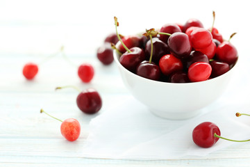 Ripe cherries in bowl on a white wooden table