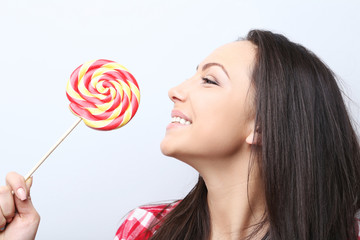 Young woman with lollipop on grey background