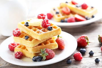Homemade waffles with berries in plate on grey wooden table