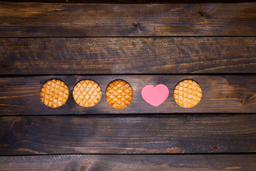 Four round cookies and pink heart made of paper