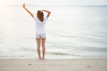 Rear of young woman standing stretch her arms in the air on the