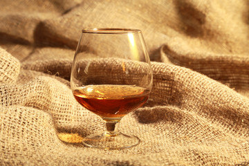 cognac in a glasses, pralines on Old textile sacking