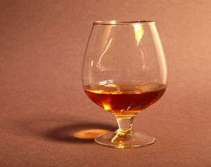 White cup of coffee and cognac in a glasses, pralines on red background.