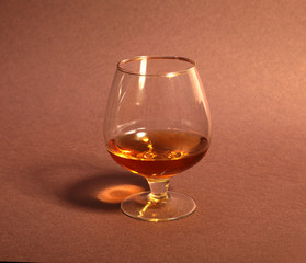White cup of coffee and cognac in a glasses, pralines on red background.